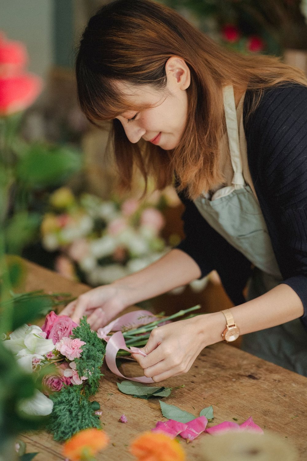 Tying a pink bouquet with ribbon on a wooden table