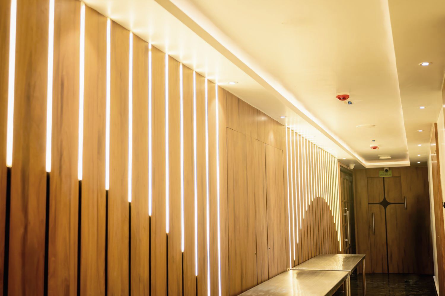 Hotel corridor lined with backlit oak battens