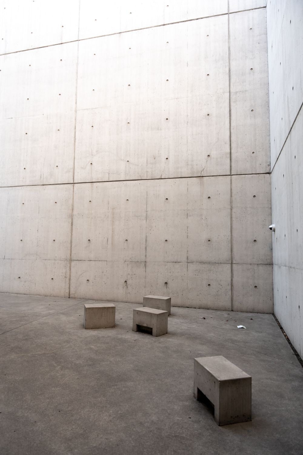 Walled courtyard with low concrete benches and a tall shaded wall