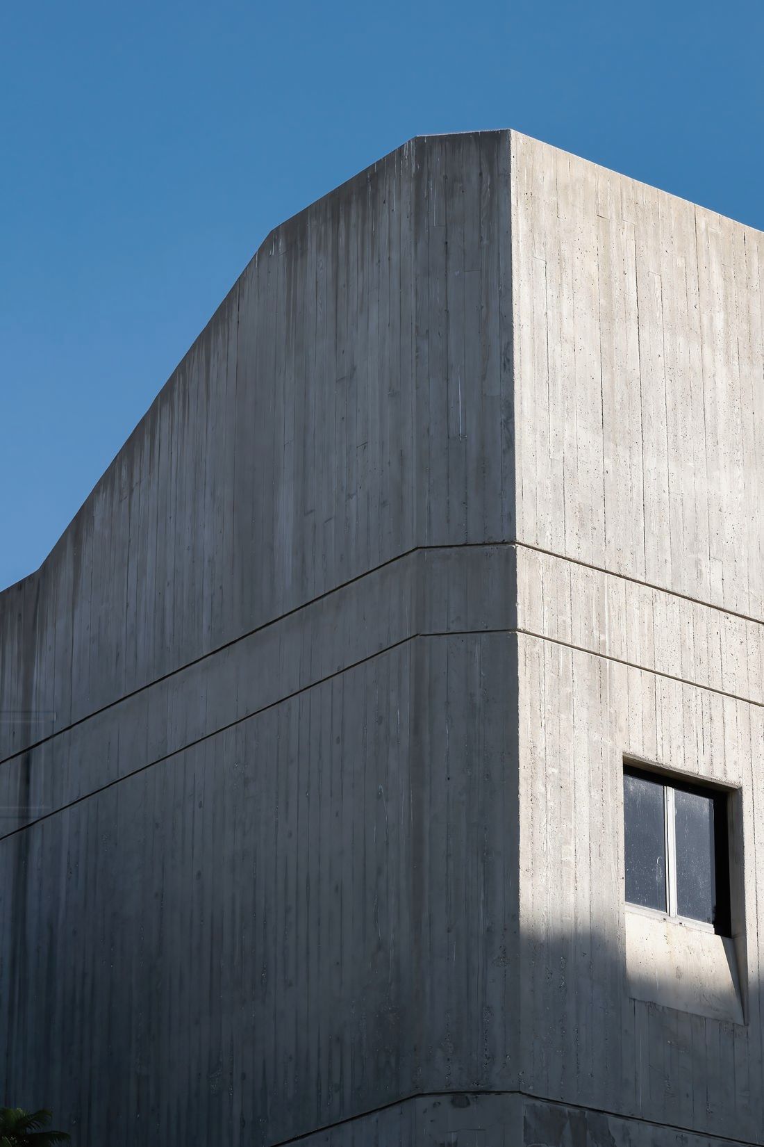 Board-marked concrete volume of Kestrel Ridge House against a clear sky