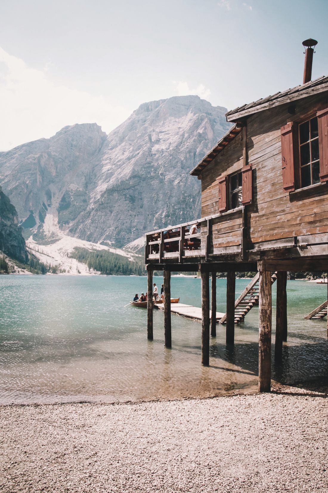 Timber lodge standing on slender piles at the edge of a mountain lake